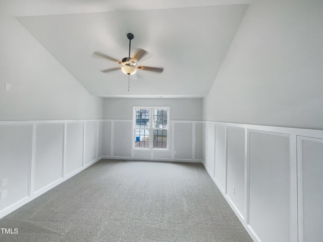 bonus room featuring vaulted ceiling, a decorative wall, ceiling fan, and carpet floors