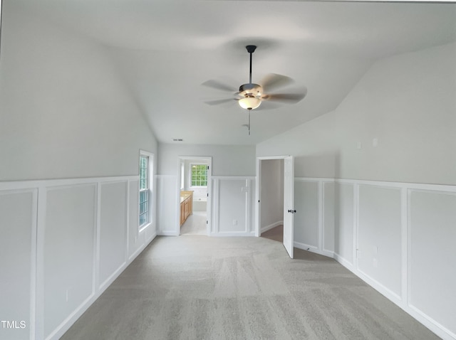 bonus room with visible vents, a wainscoted wall, light colored carpet, lofted ceiling, and a ceiling fan