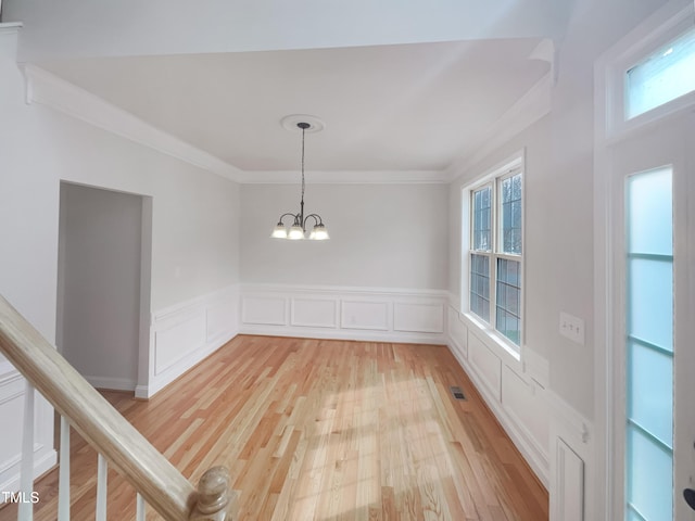 unfurnished room with visible vents, light wood-style flooring, crown molding, and an inviting chandelier