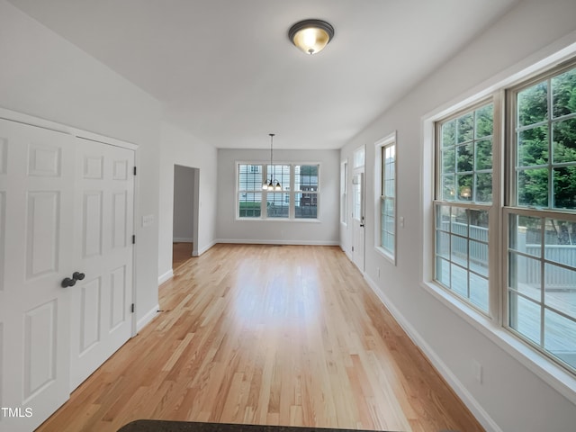 unfurnished dining area featuring light wood finished floors, an inviting chandelier, and baseboards