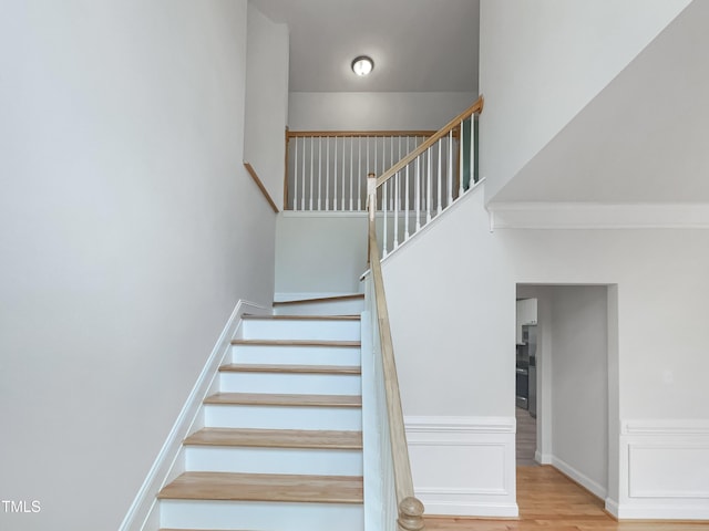 staircase featuring a high ceiling and wood finished floors