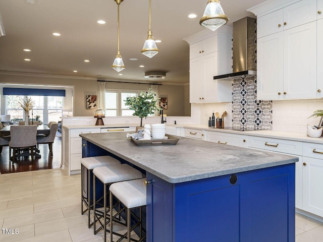 kitchen with a center island, ornamental molding, decorative backsplash, a peninsula, and wall chimney exhaust hood