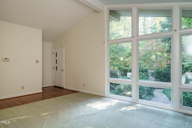 carpeted empty room with beamed ceiling, plenty of natural light, and baseboards