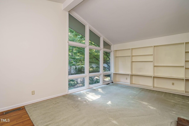 spare room featuring visible vents, lofted ceiling, and baseboards