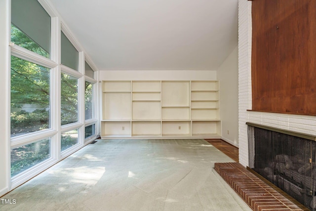 unfurnished living room with carpet, a brick fireplace, and vaulted ceiling