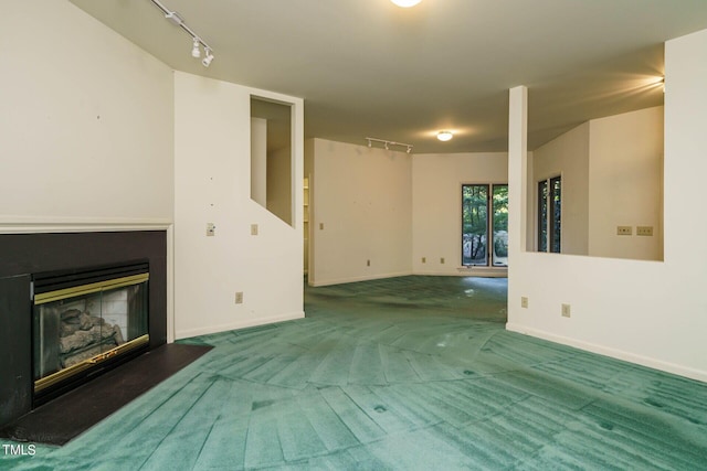 unfurnished living room with a glass covered fireplace, track lighting, baseboards, and carpet floors