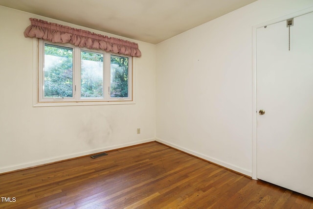 empty room with visible vents, baseboards, and hardwood / wood-style floors