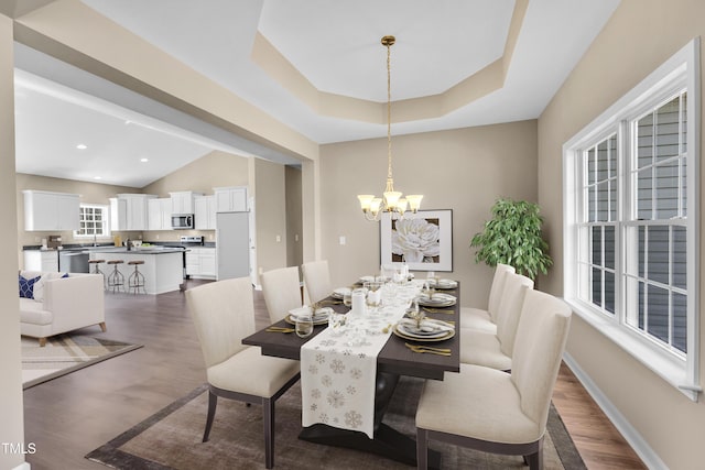 dining space with baseboards, a chandelier, dark wood finished floors, recessed lighting, and a raised ceiling