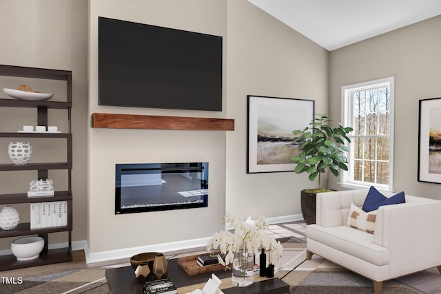 living area with a glass covered fireplace, wood finished floors, and baseboards