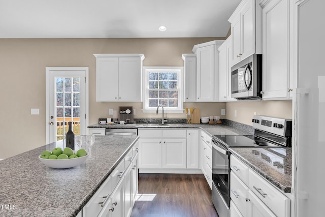 kitchen featuring a sink, light stone counters, dark wood finished floors, white cabinetry, and stainless steel appliances