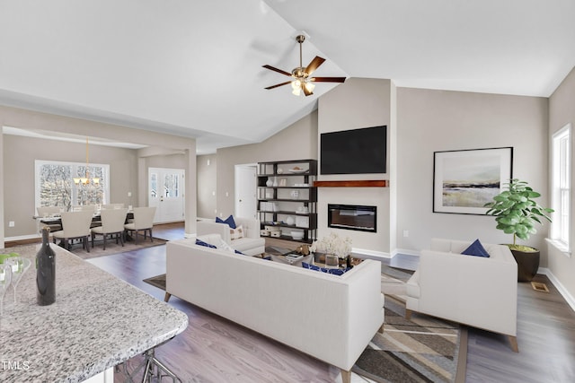 living room with wood finished floors, visible vents, baseboards, a glass covered fireplace, and ceiling fan with notable chandelier