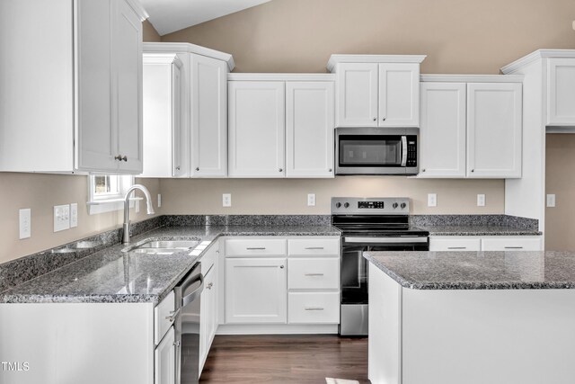 kitchen with a sink, dark stone counters, appliances with stainless steel finishes, and white cabinets