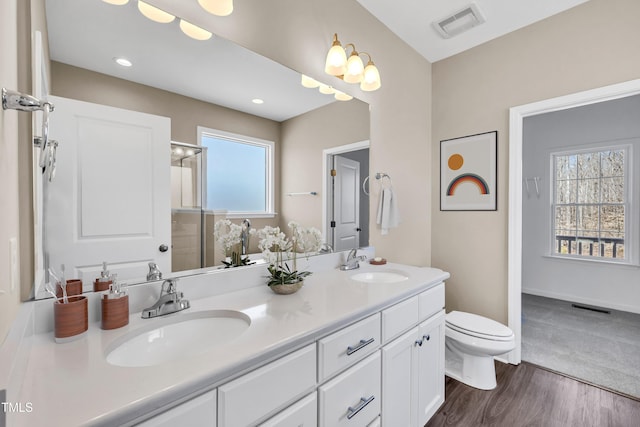 full bathroom featuring a sink, visible vents, a shower with door, and toilet