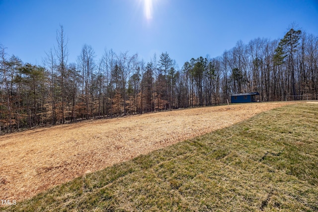 view of yard with an outbuilding, a wooded view, and a storage unit