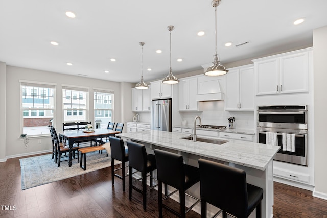 kitchen with visible vents, custom range hood, a sink, dark wood finished floors, and appliances with stainless steel finishes