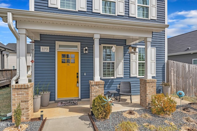 entrance to property with a porch and fence