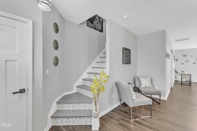 staircase featuring wood finished floors, visible vents, and baseboards