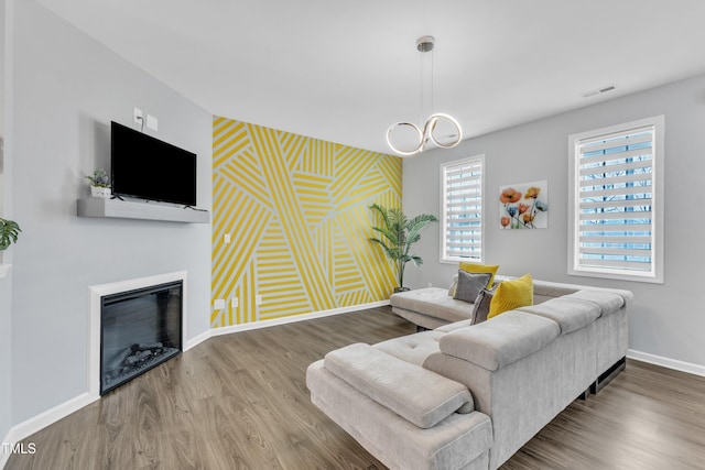 living room with a glass covered fireplace, wood finished floors, baseboards, and visible vents