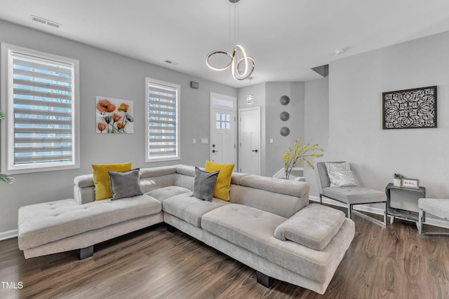 living room featuring visible vents, plenty of natural light, dark wood-type flooring, and baseboards