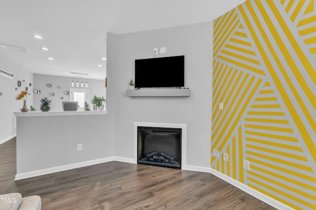 unfurnished living room with dark wood-style floors, baseboards, a fireplace, recessed lighting, and an accent wall