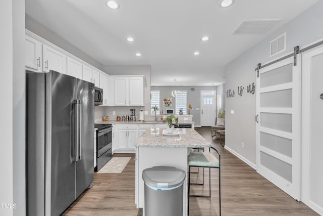 kitchen with visible vents, a center island, a barn door, appliances with stainless steel finishes, and white cabinets