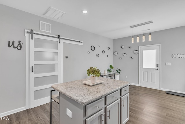 kitchen featuring visible vents, gray cabinets, a kitchen island, dark wood-style floors, and a barn door