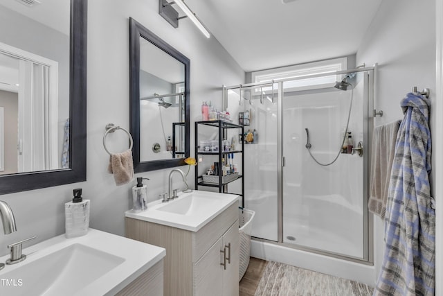 full bath with vanity, a shower stall, and wood finished floors