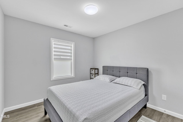 bedroom with visible vents, wood finished floors, and baseboards