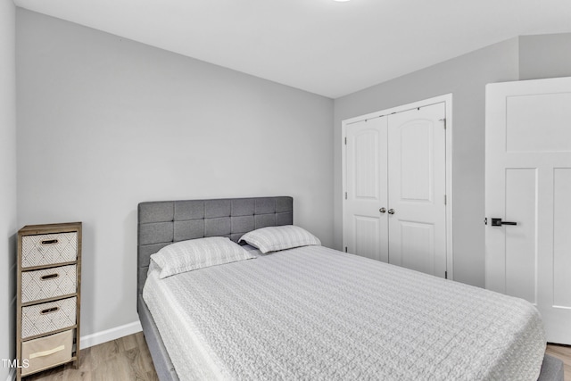 bedroom featuring wood finished floors, a closet, and baseboards