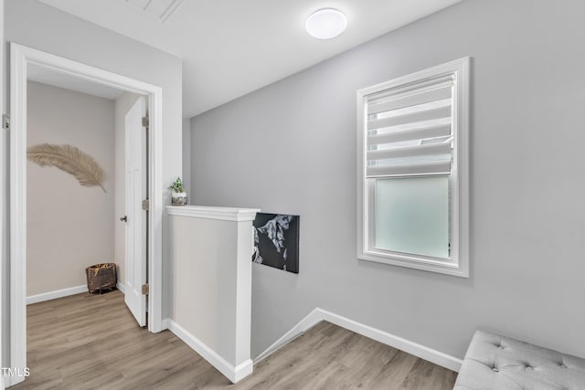 hall with an upstairs landing, visible vents, light wood-type flooring, and baseboards