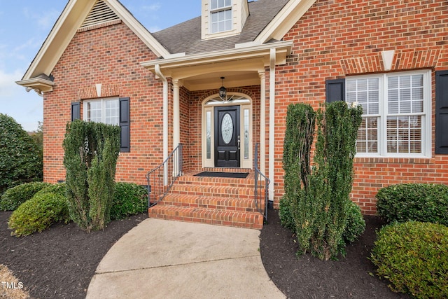 doorway to property featuring brick siding and a shingled roof