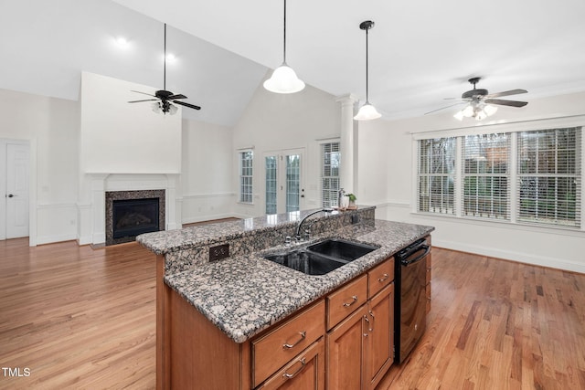 kitchen featuring an island with sink, a sink, plenty of natural light, brown cabinetry, and dishwasher