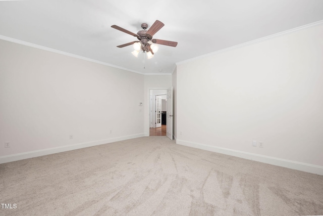 carpeted spare room with crown molding, a ceiling fan, and baseboards