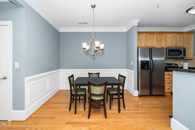 dining area with a notable chandelier, crown molding, light wood-style floors, and visible vents