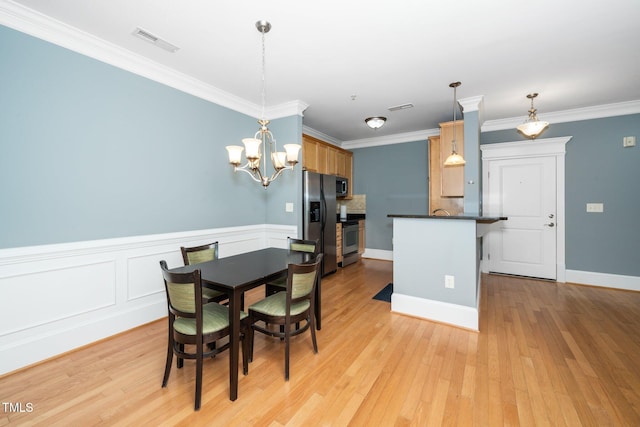 dining room with a notable chandelier, ornamental molding, visible vents, and light wood-type flooring