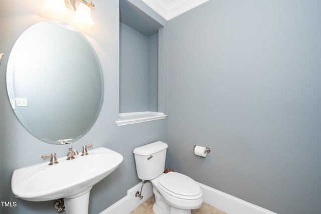 half bathroom with a sink, baseboards, toilet, and tile patterned floors