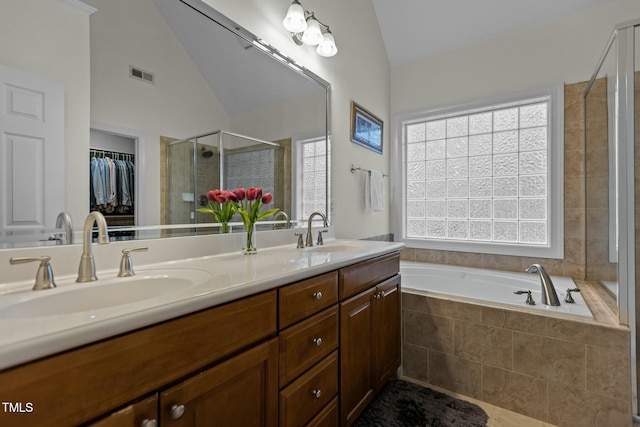 bathroom with visible vents, double vanity, a stall shower, a sink, and vaulted ceiling