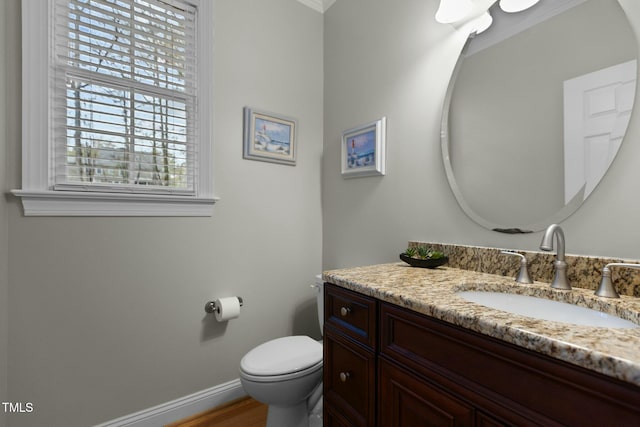 half bath featuring baseboards, toilet, wood finished floors, and vanity