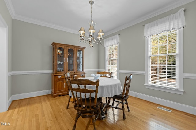 dining area with light wood-type flooring, visible vents, a notable chandelier, and crown molding