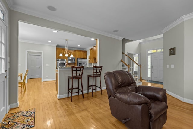 living area featuring light wood-style floors, baseboards, a chandelier, and ornamental molding