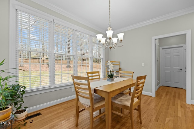 dining area featuring baseboards, visible vents, crown molding, light wood-type flooring, and a chandelier