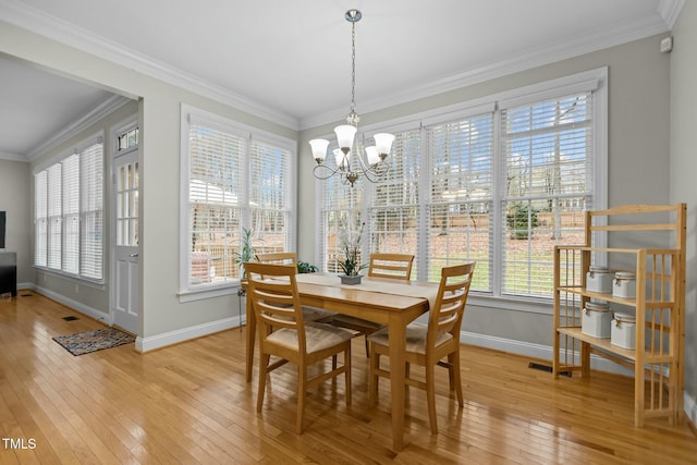 dining space featuring light wood-style flooring, baseboards, a chandelier, and ornamental molding