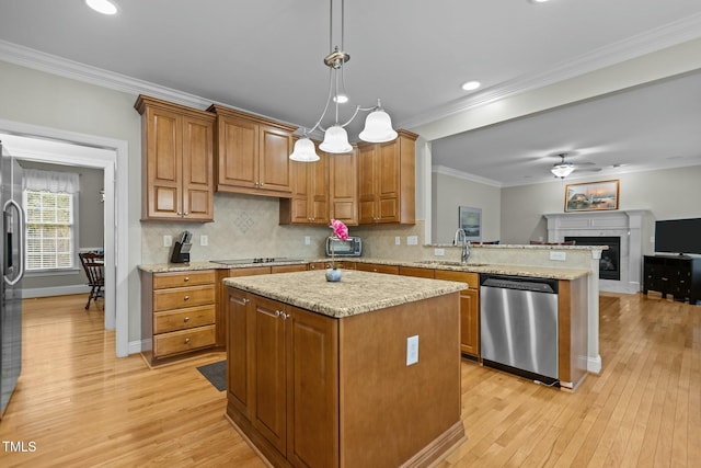 kitchen with brown cabinets, a sink, light wood-style floors, appliances with stainless steel finishes, and crown molding