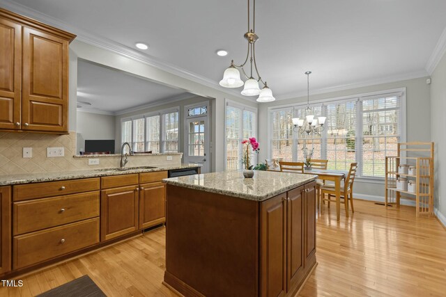 kitchen featuring brown cabinetry, a chandelier, crown molding, and a sink