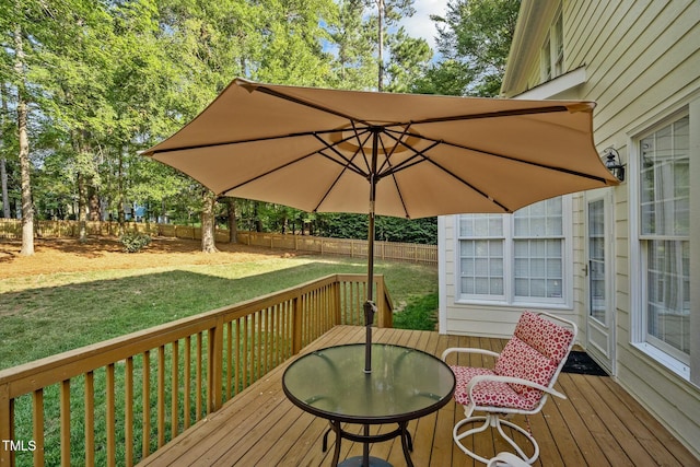 wooden terrace with outdoor dining space, fence, and a lawn