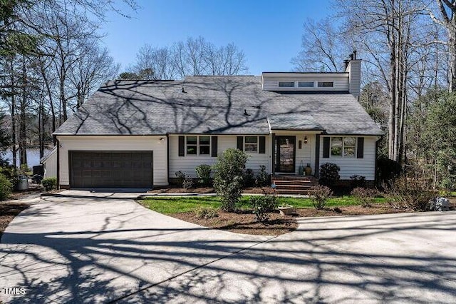 view of front of property featuring an attached garage, a chimney, and driveway