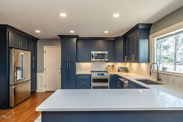 kitchen with a sink, dark wood finished floors, stainless steel appliances, light countertops, and decorative backsplash