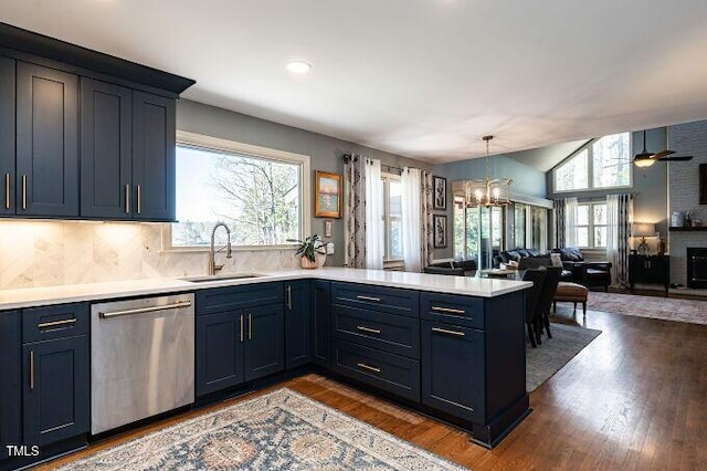 kitchen featuring dishwasher, light countertops, lofted ceiling, a peninsula, and a sink