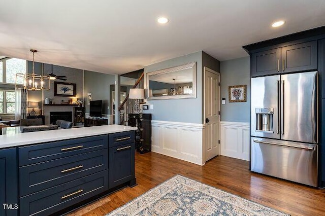 kitchen featuring dark wood finished floors, high end fridge, light countertops, wainscoting, and open floor plan