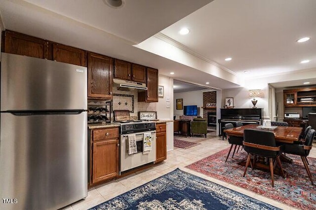 kitchen featuring freestanding refrigerator, decorative backsplash, under cabinet range hood, range with gas cooktop, and open floor plan